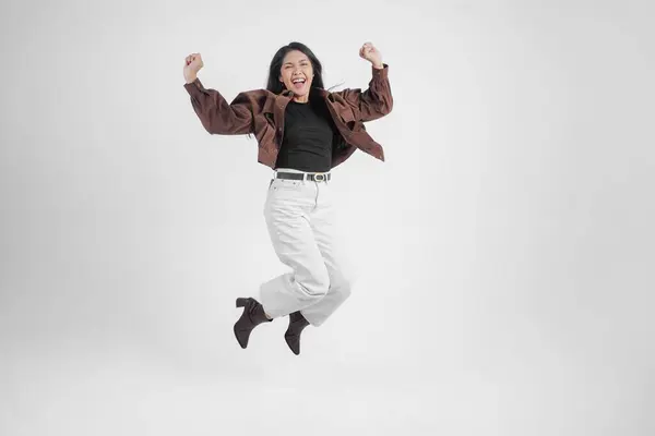 Gadis Asia Aktif Melompat Dan Mengangkat Tangan Mengenakan Jaket Coklat — Stok Foto