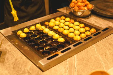 Process to cooking Takoyaki on a hot pan with ingredients on table at kitchen restaurant.