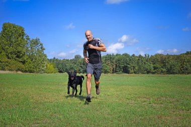 Parkta köpek ile güneşli gün koşan adam.