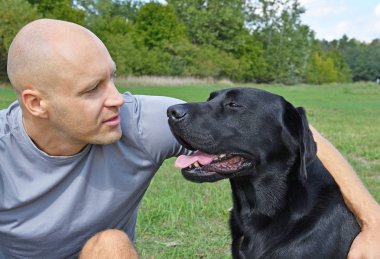 Güneşli bir gün parkta çocukla siyah köpek.
