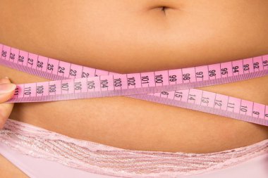 Şişman bir kadın bir göbek metre çevre ölçer.