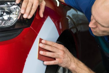 Değirmeni kağıt elinde bir adam kim araba dükkanda araba cila keskinleştirmek.