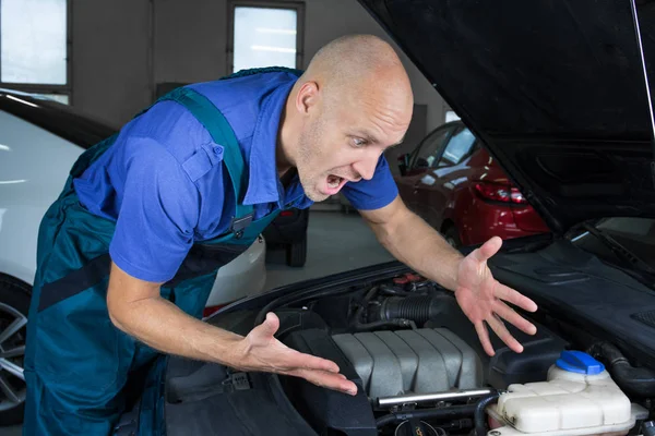 Young car service technician who repair the car engine motor.