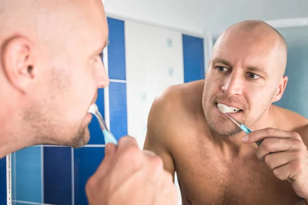 Man looks at the mirror in the bathroom.