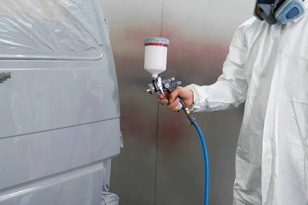 Painter spray gun in the hands of a painter.