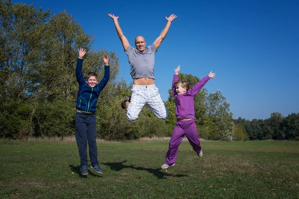 A family are jumping in the park at sunny day.