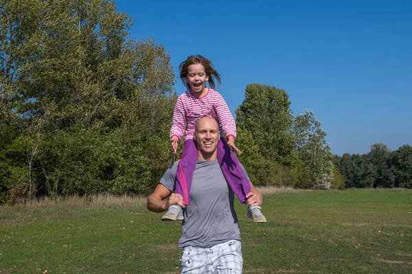 A father with daughter are playing in the park at sunny day.