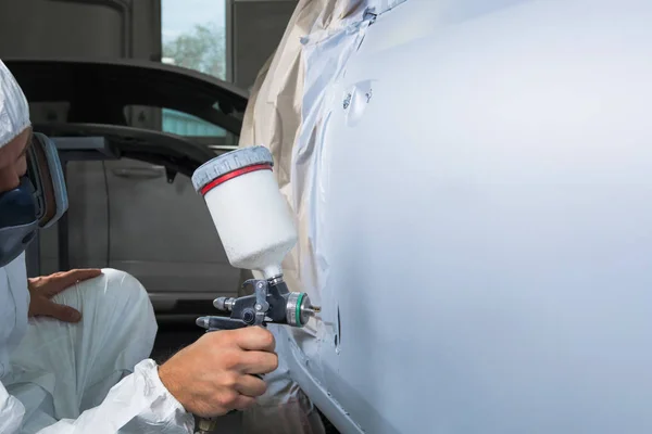 Painter spray gun in the hands of a painter.