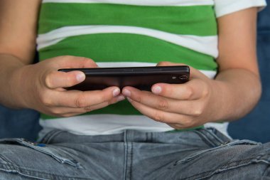 Obez küçük oturan çocuk ve oyun cep telefonu oyun.