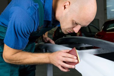 Değirmeni kağıt elinde bir adam kim araba dükkanda araba cila keskinleştirmek..