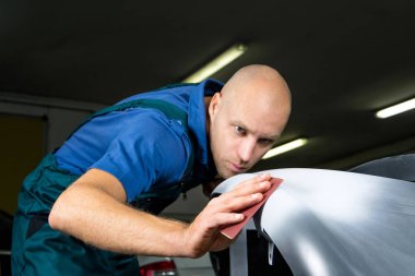 Değirmeni kağıt elinde bir adam kim araba dükkanda araba cila keskinleştirmek..