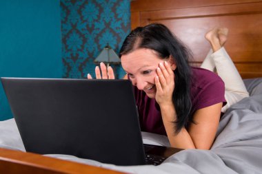 Yatakta yatarken ve bilgisayar başında arayan kadın.