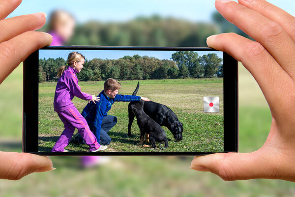 Woman with mobile phone photos children with dog.