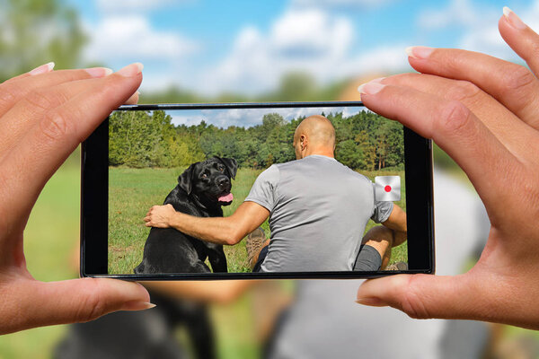 Woman with mobile phone photos man with dog.