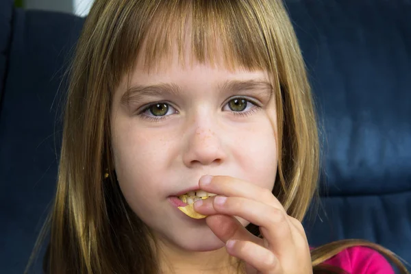 Little girl is eating chips.