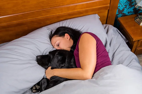 Woman sleeping in bed with dog.