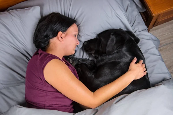 Woman sleeping in bed with dog.