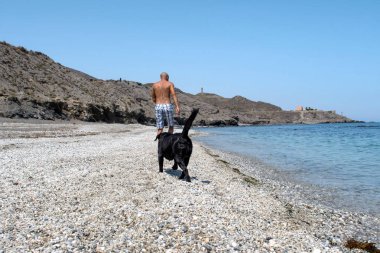 adam köpeğiyle sahilde.