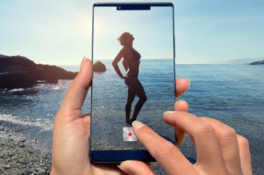 Sahilde diğer kadınla kadın cep telefonu ile fotoğraf.