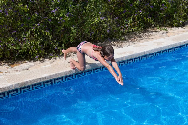 Small girl jump in the swimming pool.