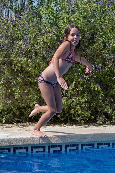 Small girl jump in the swimming pool.