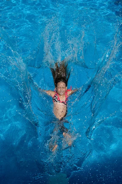 Small girl jump in the swimming pool.