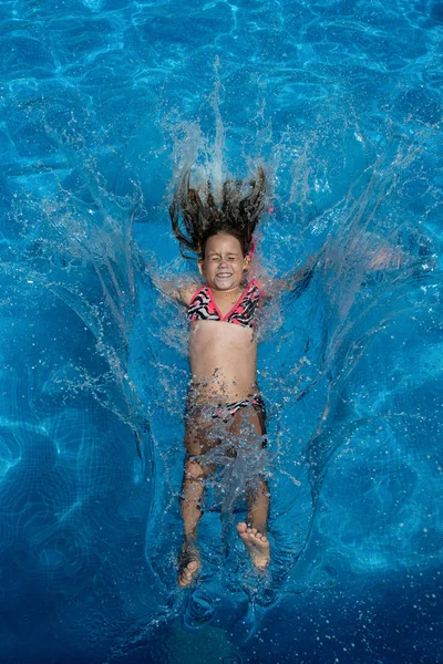 Small girl jump in the swimming pool.