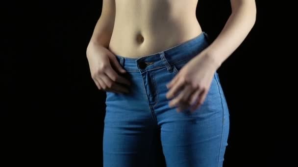 Молодая женщина раздевает синие джинсы — стоковое видео