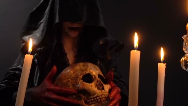 Mujer y cráneo entre velas — Vídeos de Stock