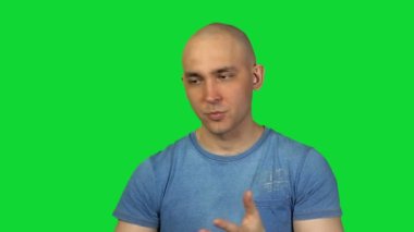 Kel adam yeşil arka plan üzerinde konuşuyor