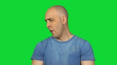 Yeşil zemin üzerine genç kel adam esniyor