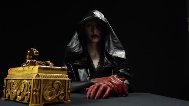 Woman in black hood opening horror box — Stock Video