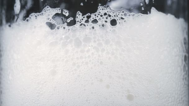 Filmagem de cerveja gelada em vidro com espuma branca — Vídeo de Stock