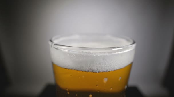 Cerveja dourada em vidro e espuma branca — Vídeo de Stock