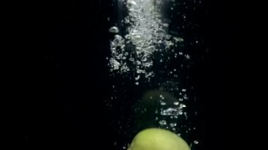 Siyah arka plan üzerine su içinde düşme görüntüleri yeşil elma