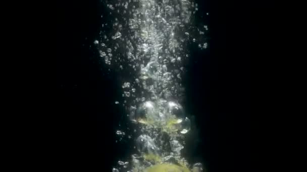 Запись двух падающих зеленых яблок в воде на черном фоне — стоковое видео