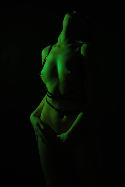 Photo of young woman in leather belt on black background