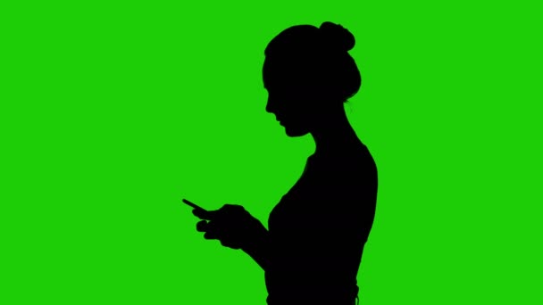 Tieners silhouet met smartphone op groene achtergrond — Stockvideo