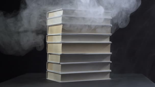 Libros entre humo sobre fondo negro — Vídeo de stock