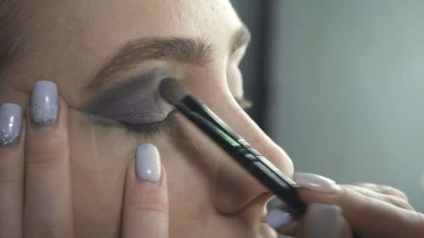 Profesional aplicando sombras de ojos en estudio de belleza — Vídeo de stock