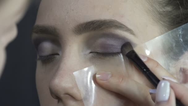 Model tijdens het aanbrengen van donkere oogschaduwen — Stockvideo