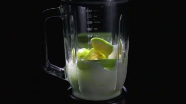 Siyah bir arka plan üzerinde bir blender sebze yüzlü sallayarak