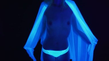 Çıplak gövdeli ve ultraviyole ışıkta beyaz kumaşlı bir kız.