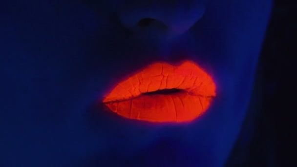 Jeune femme aux lèvres peintes en rouge à la lumière ultraviolette — Video