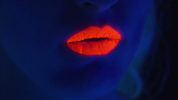 Femme aux lèvres rouges montrant la langue en lumière ultraviolette — Video