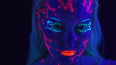 Ultraviyole ışıkta parlak makyajlı genç bir kadın