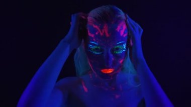 Ultraviyole ışıkta parlak vücut bağı olan genç bir kız.