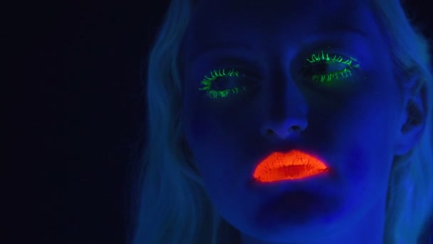 Jeune femme avec un maquillage lumineux à la lumière ultraviolette — Video