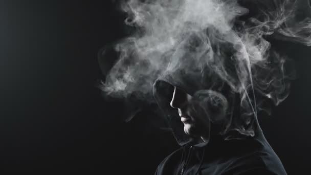 Ένας τύπος με μαύρη κουκούλα με τον καπνό μέσα. — Αρχείο Βίντεο