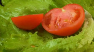 Islak yeşil marulun üzerine yarım domates düşüşü videosu.